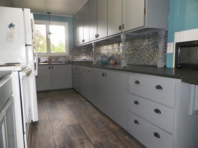 213 Cass St, Tustin, MI 49688 - kitchen featuring dark countertops, black microwave, dark wood finished floors, and decorative backsplash