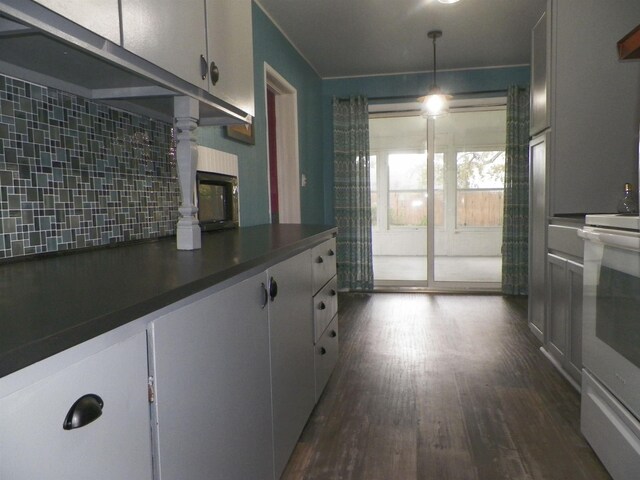 213 Cass St, Tustin, MI 49688 - kitchen featuring decorative backsplash, dark countertops, dark wood-type flooring, stove, and white cabinetry
