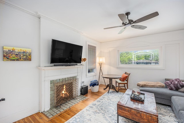 2223 S La Salle Gdns, Detroit, MI 48206 - living room featuring a tile fireplace, light wood-style flooring, ceiling fan, ornamental molding, and baseboards