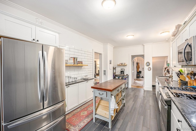 2223 S La Salle Gdns, Detroit, MI 48206 - kitchen featuring appliances with stainless steel finishes, tasteful backsplash, open shelves, arched walkways, and ornamental molding
