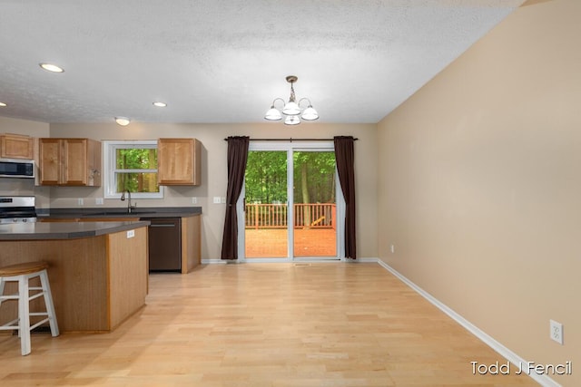 11081 Timberline Dr, Allendale, MI 49401 - kitchen with appliances with stainless steel finishes, light wood-style flooring, dark countertops, a chandelier, and baseboards