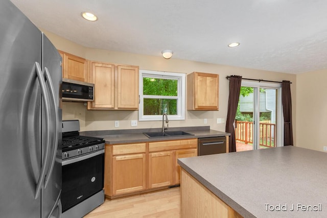 11081 Timberline Dr, Allendale, MI 49401 - kitchen featuring stainless steel appliances, a sink, light brown cabinetry, light wood-style flooring, and dark countertops