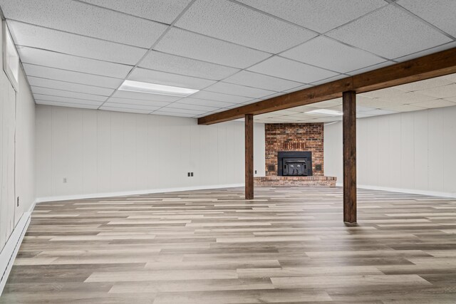 7060 Dobson Rd, Jonesville, MI 49250 - finished below grade area featuring wood finished floors, baseboards, a baseboard heating unit, and a paneled ceiling