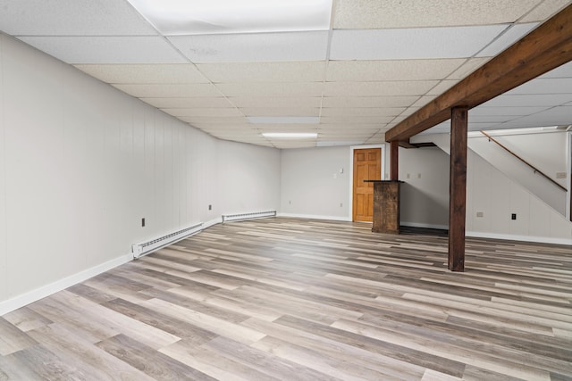 7060 Dobson Rd, Jonesville, MI 49250 - finished below grade area with baseboard heating, light wood finished floors, baseboards, and a drop ceiling