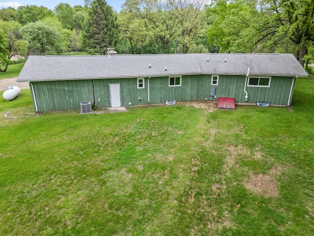 7060 Dobson Rd, Jonesville, MI 49250 - back of house featuring central AC unit, a lawn, roof with shingles, and a forest view