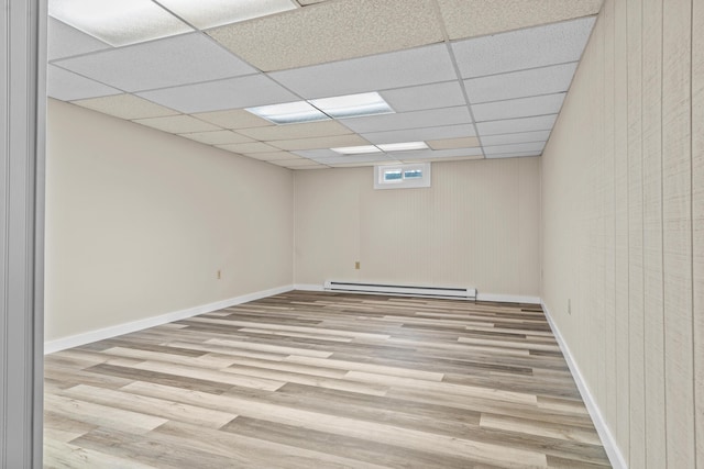 7060 Dobson Rd, Jonesville, MI 49250 - empty room with baseboard heating, wood finished floors, a paneled ceiling, and baseboards
