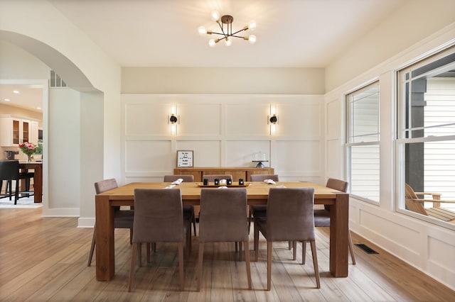 8460 Woodridge Dr, Davison, MI 48423 - dining area with a decorative wall, arched walkways, light wood-style flooring, and a chandelier