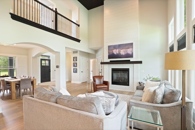 8460 Woodridge Dr, Davison, MI 48423 - living room featuring arched walkways, a high ceiling, a glass covered fireplace, and light wood-type flooring