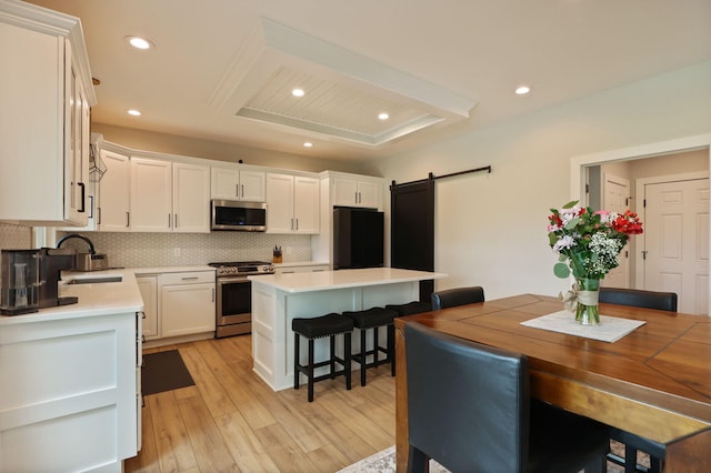 8460 Woodridge Dr, Davison, MI 48423 - kitchen with appliances with stainless steel finishes, a barn door, backsplash, white cabinetry, and recessed lighting