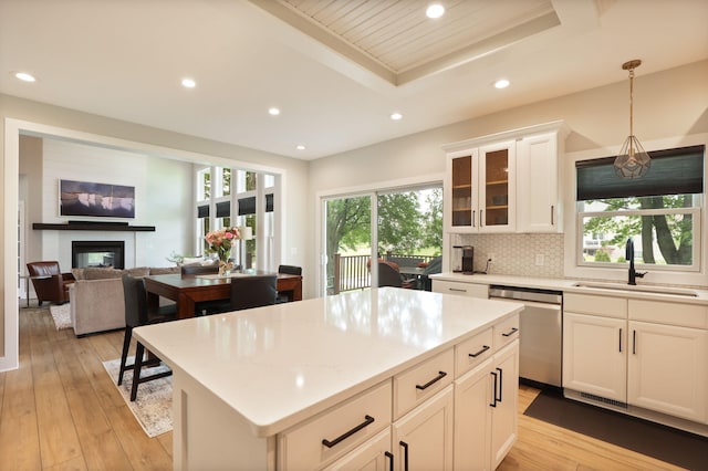 8460 Woodridge Dr, Davison, MI 48423 - kitchen with stainless steel dishwasher, recessed lighting, a glass covered fireplace, light wood-type flooring, and white cabinets