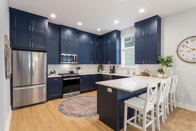 245 Cavelier Ave, Saint Joseph, MI 49085 - kitchen with appliances with stainless steel finishes, a peninsula, blue cabinetry, a breakfast bar, and recessed lighting