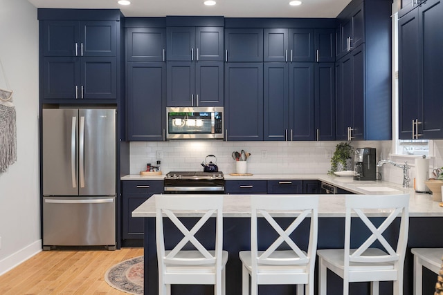245 Cavelier Ave, Saint Joseph, MI 49085 - kitchen with stainless steel appliances, a sink, blue cabinets, light wood finished floors, and recessed lighting