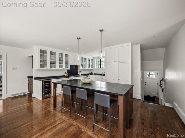 822 Suffield Ave, Birmingham, MI 48009 - kitchen featuring wine cooler, dark countertops, dark wood-style flooring, a kitchen bar, and white cabinets