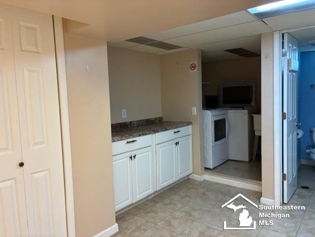 13535 Netherwood St, Southgate, MI 48195 - kitchen with washing machine and dryer, light tile patterned floors, a paneled ceiling, baseboards, and white cabinetry