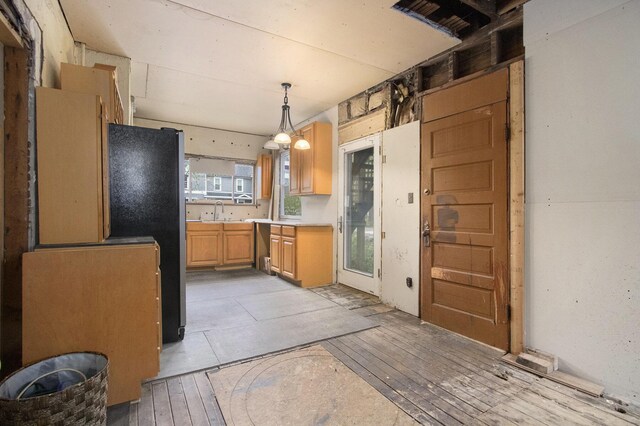 1122 Main St, Saint Joseph, MI 49085 - kitchen featuring light wood-type flooring, light countertops, freestanding refrigerator, hanging light fixtures, and a sink