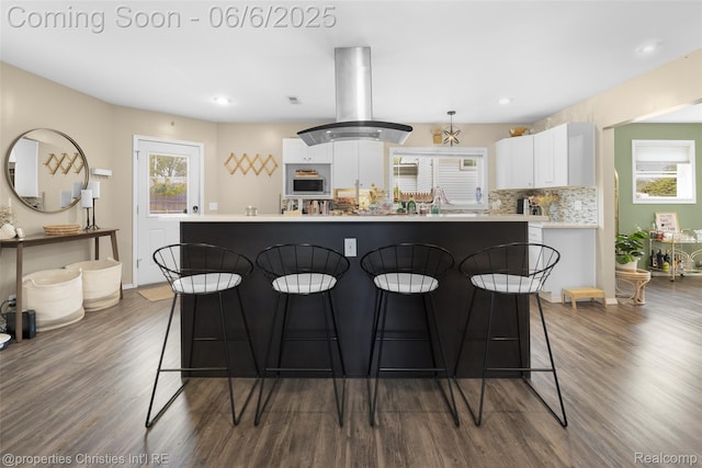 34143 Zimmer Dr, Sterling Heights, MI 48310 - kitchen featuring dark wood-type flooring, white cabinetry, a breakfast bar area, light countertops, and island exhaust hood
