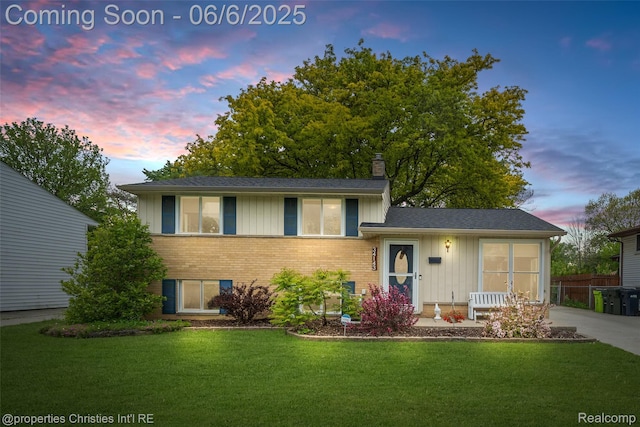 34143 Zimmer Dr, Sterling Heights, MI 48310 - split level home with board and batten siding, brick siding, a front lawn, and a chimney