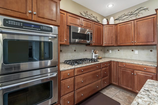 4132 Winding Way, Kalamazoo, MI 49004 - kitchen with stainless steel appliances, backsplash, light stone counters, light tile patterned flooring, and brown cabinets