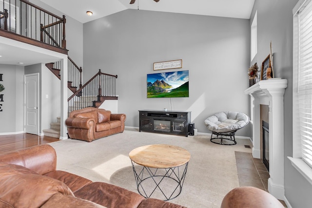 449 Corinth Cir, Dundee, MI 48131 - carpeted living room with a fireplace with flush hearth, high vaulted ceiling, ceiling fan, stairway, and baseboards