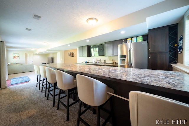 8718 Little Bend Ct, Middleville, MI 49333 - kitchen featuring stainless steel refrigerator with ice dispenser, a kitchen breakfast bar, carpet flooring, recessed lighting, and a sink