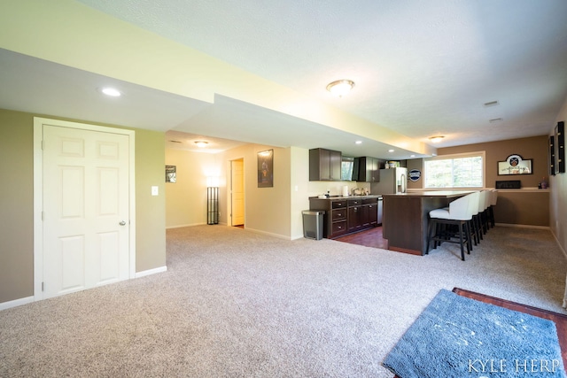 8718 Little Bend Ct, Middleville, MI 49333 - living area with dark colored carpet, bar with sink, and baseboards