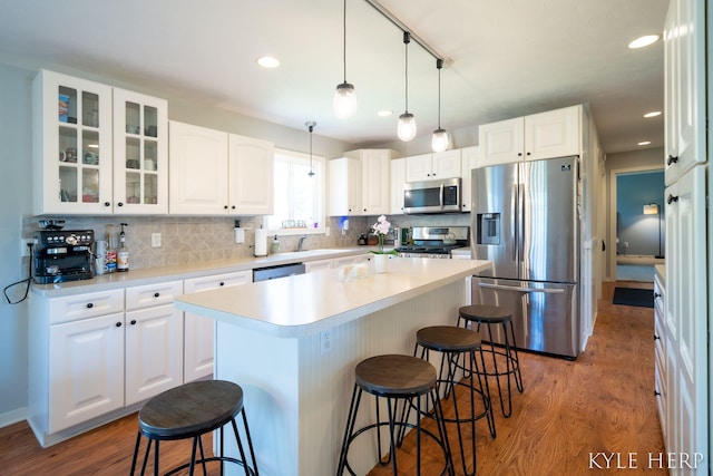 8718 Little Bend Ct, Middleville, MI 49333 - kitchen with stainless steel appliances, a breakfast bar area, wood finished floors, backsplash, and glass insert cabinets