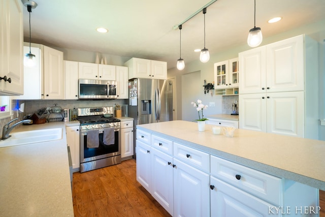 8718 Little Bend Ct, Middleville, MI 49333 - kitchen featuring appliances with stainless steel finishes, a sink, decorative backsplash, wood finished floors, and light countertops