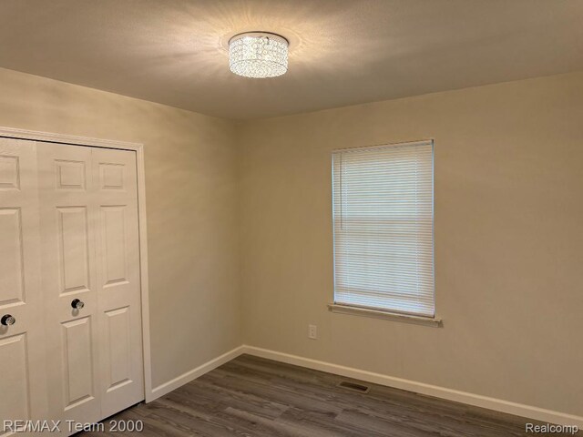 29054 Burning Tree Ln, Romulus, MI 48174 - unfurnished bedroom featuring baseboards, dark wood finished floors, a chandelier, and a closet