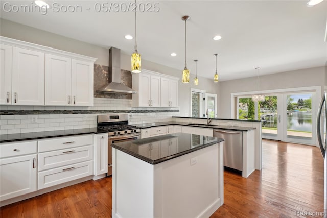 13525 Torrey Rd, Fenton, MI 48430 - kitchen featuring appliances with stainless steel finishes, wall chimney range hood, a sink, a peninsula, and wood finished floors
