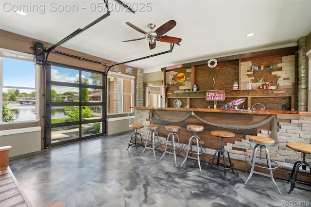 13525 Torrey Rd, Fenton, MI 48430 - indoor wet bar featuring finished concrete floors, a ceiling fan, and a water view