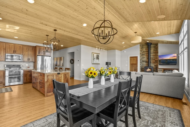 333 S W Silver Lake Rd, Michigan, MI 49685 - dining room featuring a wood stove, a chandelier, light wood finished floors, recessed lighting, and lofted ceiling