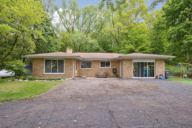 5245 Puetz Rd, Stevensville, MI 49127 - view of front of property with a playground, a chimney, brick siding, and asphalt driveway