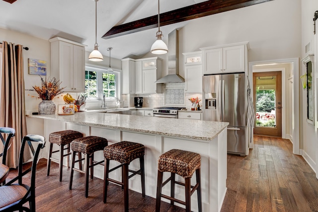283 Wiley Rd, Douglas, MI 49406 - kitchen with stainless steel appliances, wall chimney range hood, backsplash, a peninsula, and a breakfast bar