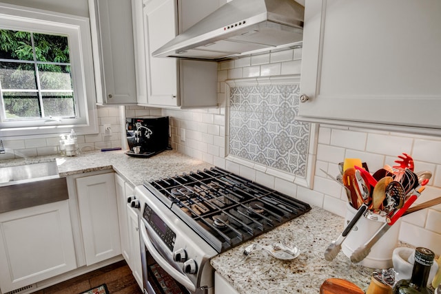 283 Wiley Rd, Douglas, MI 49406 - kitchen with gas stove, wall chimney exhaust hood, backsplash, white cabinets, and light stone counters