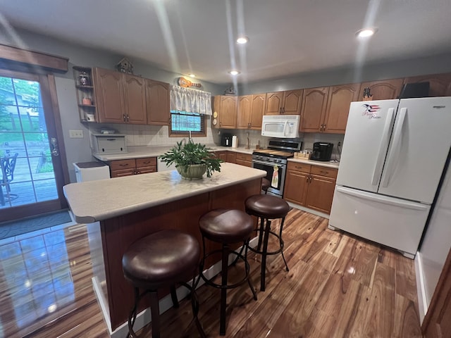 12050 S Ponderosa, Sand Lake, MI 49343 - kitchen with white appliances, light countertops, wood finished floors, a center island, and a breakfast bar area