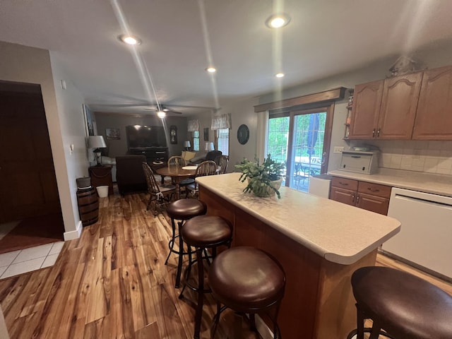 12050 S Ponderosa, Sand Lake, MI 49343 - kitchen with white dishwasher, light countertops, a breakfast bar area, light wood-style flooring, and a kitchen island