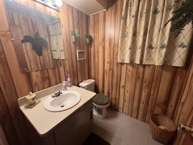 12050 S Ponderosa, Sand Lake, MI 49343 - bathroom featuring wooden walls, toilet, and vanity