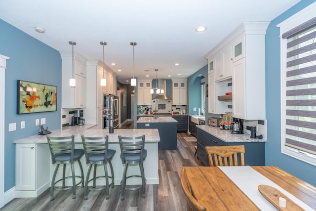 10543 Lakeshore Dr, West Olive, MI 49460 - kitchen featuring wall chimney exhaust hood, a peninsula, dark wood-style flooring, a center island, and recessed lighting
