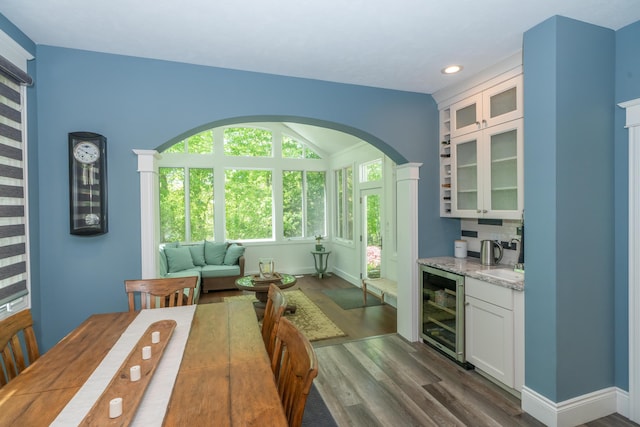 10543 Lakeshore Dr, West Olive, MI 49460 - dining space featuring wine cooler, dark wood finished floors, wet bar, arched walkways, and recessed lighting