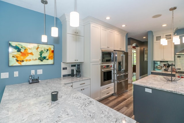 10543 Lakeshore Dr, West Olive, MI 49460 - kitchen featuring appliances with stainless steel finishes, dark wood finished floors, tasteful backsplash, light stone counters, and recessed lighting
