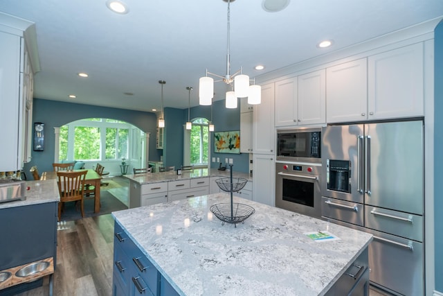 10543 Lakeshore Dr, West Olive, MI 49460 - kitchen featuring appliances with stainless steel finishes, a kitchen island, white cabinetry, dark wood-style floors, and light stone countertops