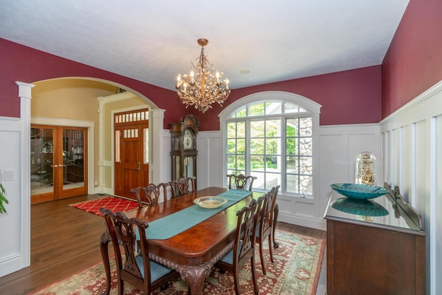 10543 Lakeshore Dr, West Olive, MI 49460 - dining room featuring a decorative wall, wood finished floors, arched walkways, a chandelier, and decorative columns