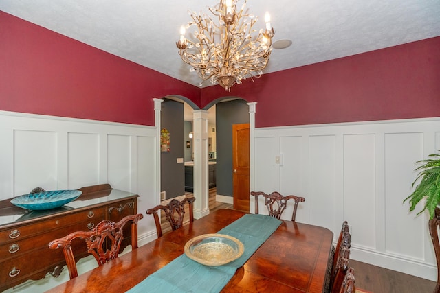 10543 Lakeshore Dr, West Olive, MI 49460 - dining space with decorative columns, a decorative wall, dark wood-style flooring, a wainscoted wall, and arched walkways