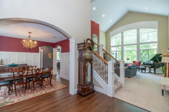 10543 Lakeshore Dr, West Olive, MI 49460 - stairway with arched walkways, high vaulted ceiling, wood finished floors, a chandelier, and decorative columns