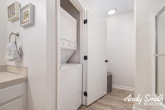 319 Nestlewood Dr Unit 3, Holland, MI 49424 - washroom featuring stacked washer / drying machine, light wood-style flooring, and baseboards