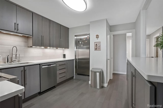 1050 Wall St Unit 8F, Ann Arbor, MI 48105 - kitchen with stainless steel appliances, a sink, tasteful backsplash, light wood-type flooring, and light countertops