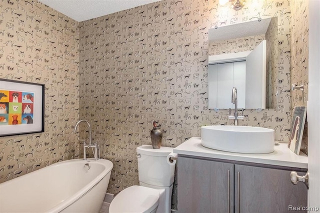 1050 Wall St Unit 8F, Ann Arbor, MI 48105 - bathroom featuring wallpapered walls, a soaking tub, vanity, toilet, and a textured ceiling