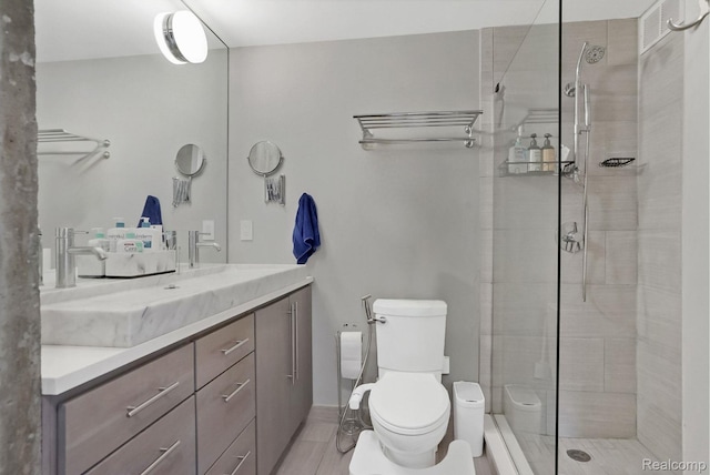 1050 Wall St Unit 8F, Ann Arbor, MI 48105 - bathroom featuring toilet, vanity, a tile shower, and tile patterned flooring