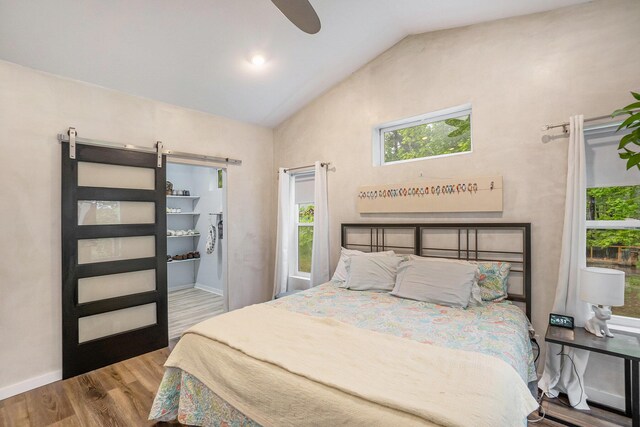 4958 Juniper Rdg, Newaygo, MI 49337 - bedroom featuring wood finished floors, baseboards, a barn door, a ceiling fan, and high vaulted ceiling