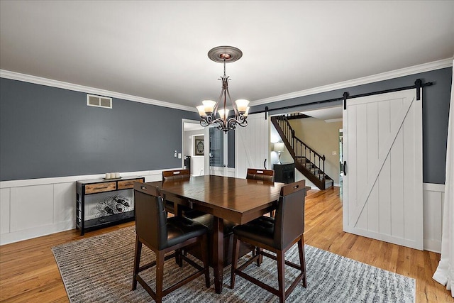 4047 Ramsgate Ct, Ann Arbor, MI 48103 - dining space with a barn door, a chandelier, ornamental molding, light wood finished floors, and a wainscoted wall